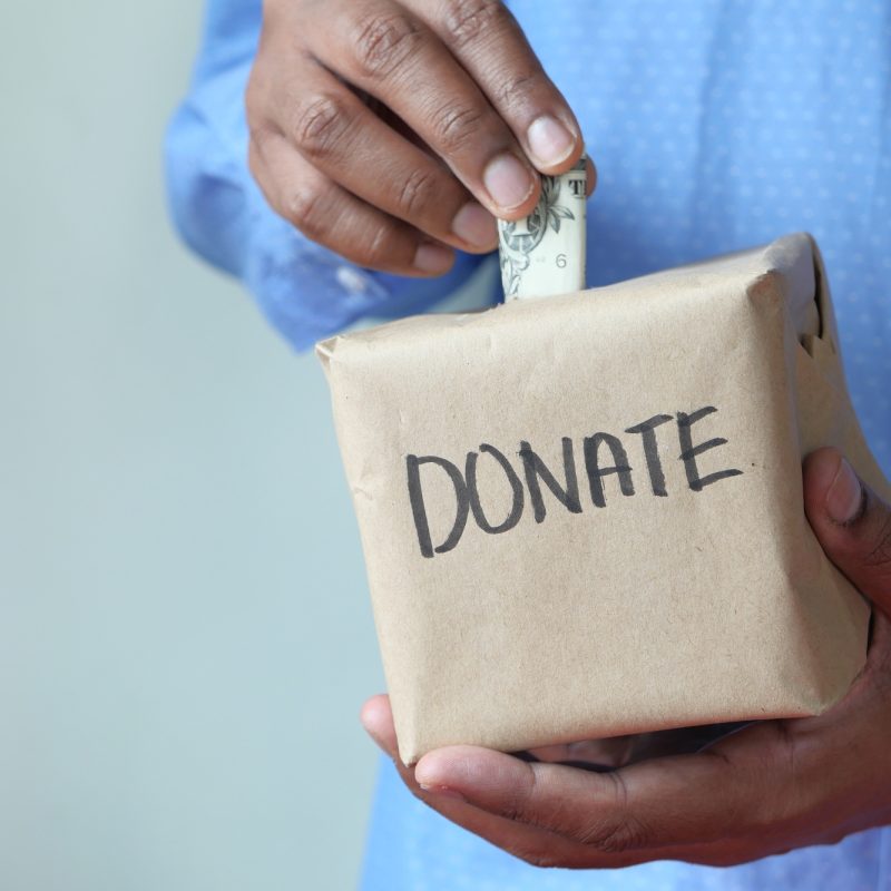 Man puts donation in a box with copy space .